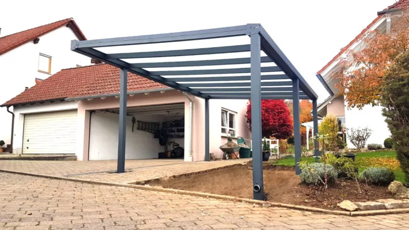 Carport aus Aluminium in Anthrazit mit Glaseindeckung vor einem Haus